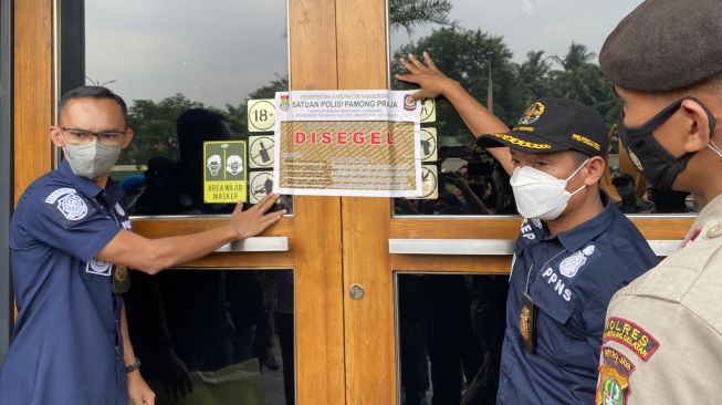 Petugas gabungan dari Satpol-PP, TNI dan Polisi menyegel outlet Holywings di Karawaci, Rabu (29/6/2022). [SuaraJakarta.id/Wivy]