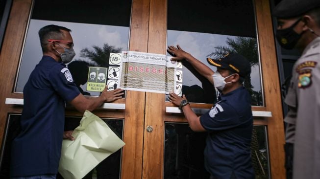 Petugas gabungan memasang stiker penyegelan gerai Holywings di kawasan Lippo Karawaci, Kabupaten Tangerang, Banten, Rabu (29/6/2022). ANTARA FOTO/Fauzan