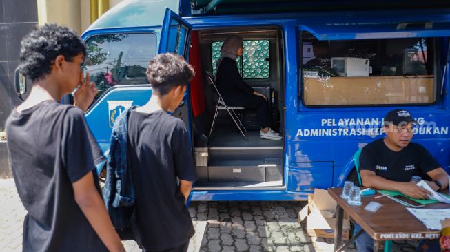 Warga mengantri untuk perekaman ulang E-KTP saat mengunjungi pelayanan keliling Dinas Kependudukan dan Pencatatan Sipil Provinsi DKI Jakarta di halaman Masjid Al Hikmah Hidayah, Cipayung, Jakarta Timur, Rabu (29/6/2022). [Suara.com/Alfian Winanto]