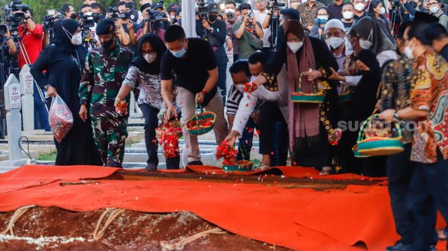 Keluarga menabur bunga ke dalam pusara Menteri Pendayagunaan Aparatur Negara dan Reformasi Birokrasi (Menpan RB) Tjahjo Kumolo saat prosesi pemakaman di Taman Makam Pahlawan, Kalibata, Jakarta Selatan, Jumat (1/7/2022). [Suara.com/Alfian Winanto]