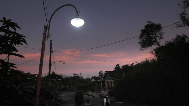 Warga melintas di dekat lampu penerangan jalan yang dihasilkan dari listrik dengan bahan bakar biogas kotoran sapi di Dangean, Gedangan, Cepogo, Boyolali, Jawa Tengah, Kamis (30/6/2022). ANTARA FOTO/Aloysius Jarot Nugroho