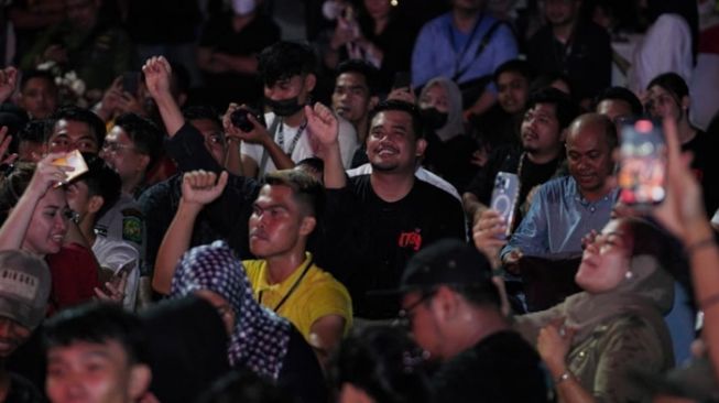 Wali Kota Medan Bobby Nasution Duduk Lesehan dan Ikut Disiram Mobil Damkar saat Konser HUT Kota Medan. [dok Pemkot Medan] 