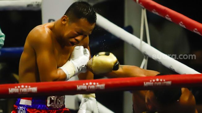 Petinju Thailand Panya Uthok (hitam) menyerang petinju Indonesia Daud Yordan (merah) dalam laga mempertahankan gelar juara kelas ringan super World Boxing Council atau WBC Asian Boxing Council Silver di Balai Sarbini, Jakarta Pusat, Jumat (1/7/2022). [Suara.com/Alfian Winanto]