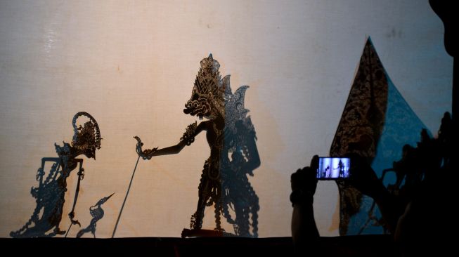 Warga memotret pementasan wayang kulit dengan lakon 'Hanoman Duta Negara' yang ditampilkan oleh dalang Gunarto Gunotalijendro dalam pagelaran seni rangkaian Pesta Kesenian Bali (PKB) 2022 di Denpasar, Bali, Sabtu (2/7/2022). [ANTARA FOTO/Fikri Yusuf/rwa]