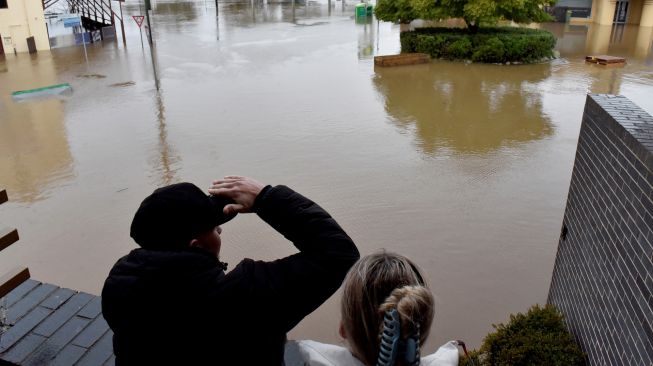 Warga melihat jalan-jalan yang terendam banjir akibat hujan deras di pinggiran Camden, Sydney, Australia, Minggu (3/7/2022). [Muhammad FAROOQ / AFP]
