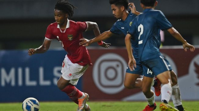 Pesepak bola Tim Nasional Indonesia U-19 Ronaldo Kwateh (kiri) berebut bola dengan pesepak bola Tim Nasional Brunei Darussalam U-19 Mohammad Hirman (tengah) dalam laga penyisihan Grup A Piala AFF U-19 2022 di Stadion Patriot Candrabhaga, Bekasi, Jawa Barat, Senin (4/7/2022). [ANTARA FOTO/Fakhri Hermansyah/wsj]