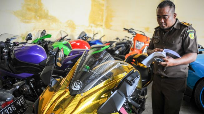 Petugas mendata barang bukti berupa motor sport dari kasus penipuan investasi opsi biner di Kejaksaan Negeri Kabupaten Bandung, Jawa Barat, Selasa (5/7/2022). [ANTARA FOTO/Raisan Al Farisi/foc]