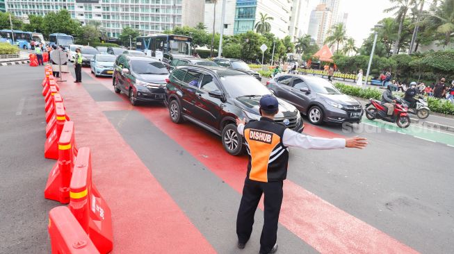 Petugas gabungan yang terdiri dari Ditlantas Polda Metro Jaya dan Dinas Perhubungan (Dishub) DKI Jakarta mengatur arus lalu lintas di kawasan Bundaran Hotel Indonesia (HI) , Jakarta Pusat, Rabu (6/7/2022). [Suara.com/Alfian Winanto]