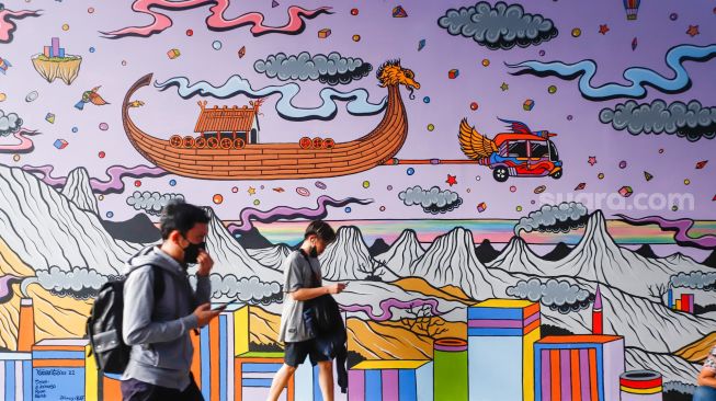 Warga melintas di dekat mural kolaborasi bergambar Thor di Terowongan Kendal, Jakarta Pusat, Selasa (5/7/2022). [Suara.com/Alfian Winanto]