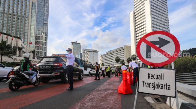 Petugas gabungan yang terdiri dari Ditlantas Polda Metro Jaya dan Dinas Perhubungan (Dishub) DKI Jakarta mengatur arus lalu lintas di kawasan Bundaran Hotel Indonesia (HI) , Jakarta Pusat, Rabu (6/7/2022). [Suara.com/Alfian Winanto]