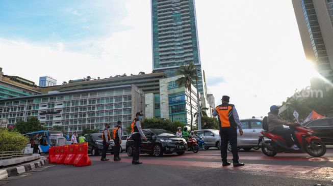 Petugas gabungan yang terdiri dari Ditlantas Polda Metro Jaya dan Dinas Perhubungan (Dishub) DKI Jakarta mengatur arus lalu lintas di kawasan Bundaran Hotel Indonesia (HI) , Jakarta Pusat, Rabu (6/7/2022). [Suara.com/Alfian Winanto]