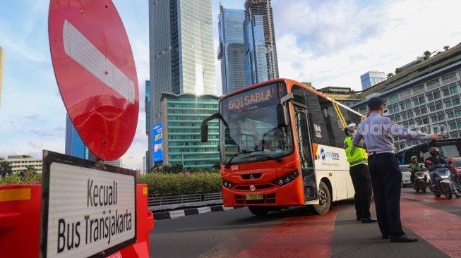 Petugas gabungan yang terdiri dari Ditlantas Polda Metro Jaya dan Dinas Perhubungan (Dishub) DKI Jakarta mengatur arus lalu lintas di kawasan Bundaran Hotel Indonesia (HI) , Jakarta Pusat, Rabu (6/7/2022). [Suara.com/Alfian Winanto]