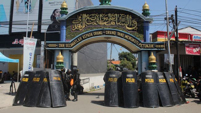 Polisi berjaga di depan gerbang Pondok Pesantren Shiddiqiyyah Ploso saat proses upaya penangkapan Moch Subchi Azal Tsani (MSAT) di Jombang, Jawa Timur, Kamis (7/7/2022).  ANTARA FOTO/Syaiful Arif
