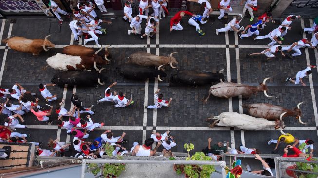 Para peserta berlari di depan banteng selama acara "encierro" (lari banteng) saat festival San Fermin di Pamplona, Spanyol, Kamis (7/7/2022). [MIGUEL RIOPA / AFP]
