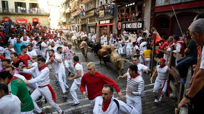 Para peserta berlari di depan banteng selama acara "encierro" (lari banteng) saat festival San Fermin di Pamplona, Spanyol, Kamis (7/7/2022). [MIGUEL RIOPA / AFP]
