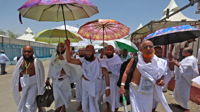 Jamaah haji berjalan dengan payung di Mina dekat kota suci Makkah, Arab Saudi, Kamis (7/7/2022). [Delil SOULEIMAN / AFP]