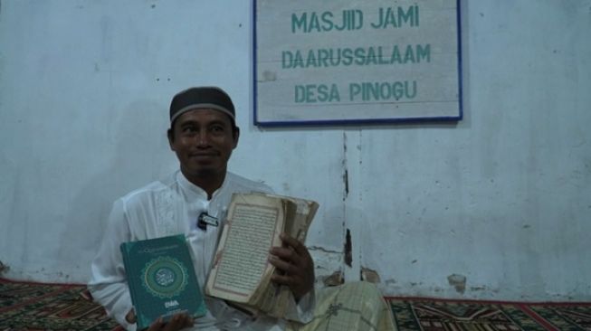 Ustaz Kasmad Sabubu pengurus masjid Jami Darussalam Desa Pinogu, Gorontalo memegang Alquran wakaf dari BWA (kiri) dan Alquran milik masjid. [dokumentasi pribadi]