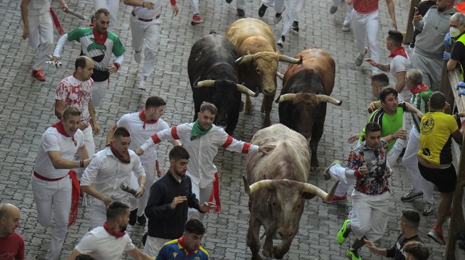 Para peserta berlari di depan banteng selama acara "encierro" (lari banteng) saat festival San Fermin di Pamplona, Spanyol, Kamis (7/7/2022). [MIGUEL RIOPA / AFP]
