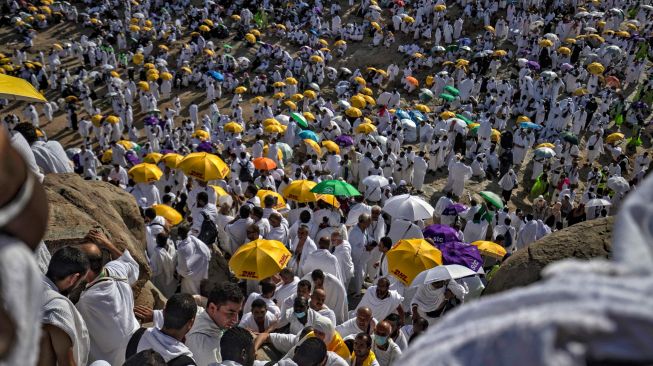 Jamaah haji mendaki Gunung Arafah atau Jabal Rahmah untuk memanjatkan doa saat melaksanakan ibadah wukuf di Arafah, tenggara kota suci Makkah, Jumat (8/7/2022). [Delil SOULEIMAN / AFP]