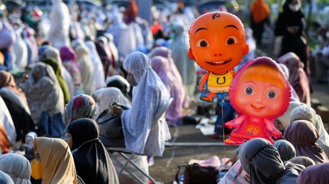 Sejumlah umat Islam membawa balon karakter animasi saat mendengarkan khutbah usai melaksanakan salat Idul Adha 1443 Hijriah di halaman Jakarta International Equestrian Park (JIEP) Pulomas, Jakarta, Sabtu (9/7/2022). [ANTARA FOTO/M Risyal Hidayat/nym]