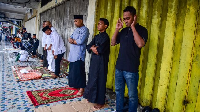 Sejumlah umat muslim Shalat Id di emperan toko seberang Masjid Raya Al Fatah untuk menghindari hujan saat peringatan Idul Adha 1443 Hijriah di Kota Ambon, Provinsi Maluku, Minggu (10/7/2022). Antara Foto