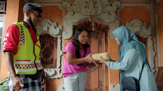 Panitia kurban dari Lembaga Dakwah Islam Indonesia (LDII) Provinsi Bali memberikan daging kurban kepada warga Bali saat tradisi Ngejot pada Hari Raya Idul Adha 1443 Hijriah di Denpasar, Bali, Minggu (10/7/2022).  ANTARA FOTO/Nyoman Hendra Wibowo