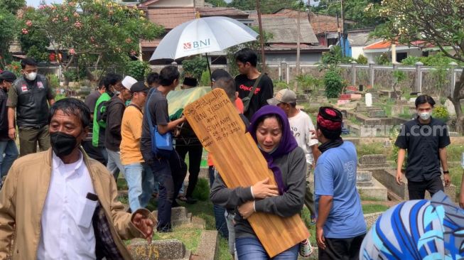 Pemakaman Rini S Bon Bon di TPU Kawi-Kawi di kawasan Johar Baru, Jakarta Pusat, Senin (11/7/2022). Tampak seorang kerabat menangis sambil membawa papan nisan almarhumah. [Adiyoga Priyambodo/Suara.com]