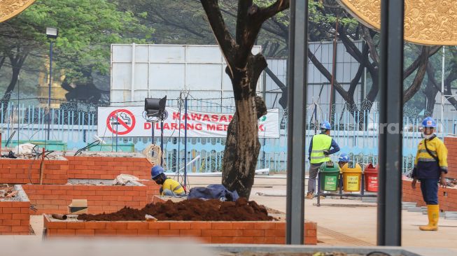 Pekerja beraktivitas di proyek revitalisasi Taman Mini Indonesia Indah (TMII), Jakarta Timur, Selasa (12/7/2022). [Suara.com/Alfian Winanto]
