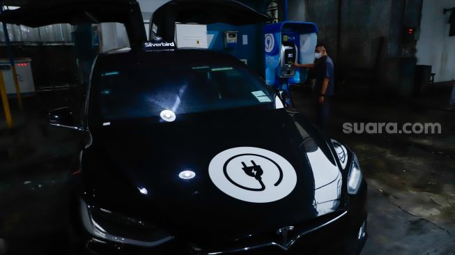 Pengemudi mengisi daya mobil taksi listrik (e-Taxi) di Kantor Pusat Bluebird Group, Mampang Prapatan, Jakarta Selatan, Rabu (13/7/2022). [Suara.com/Alfian Winanto]