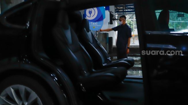 Pengemudi mengisi daya mobil taksi listrik (e-Taxi) di Kantor Pusat Bluebird Group, Mampang Prapatan, Jakarta Selatan, Rabu (13/7/2022). [Suara.com/Alfian Winanto]