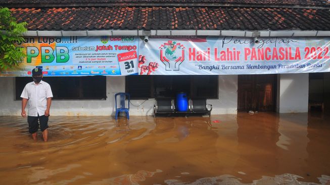 Warga berdiri di depan balai desa yang terdampak banjir di Desa Golantepus, Mejobo, Kudus, Jawa Tengah, Kamis (14/7/2022). ANTARA FOTO/Yusuf Nugroho