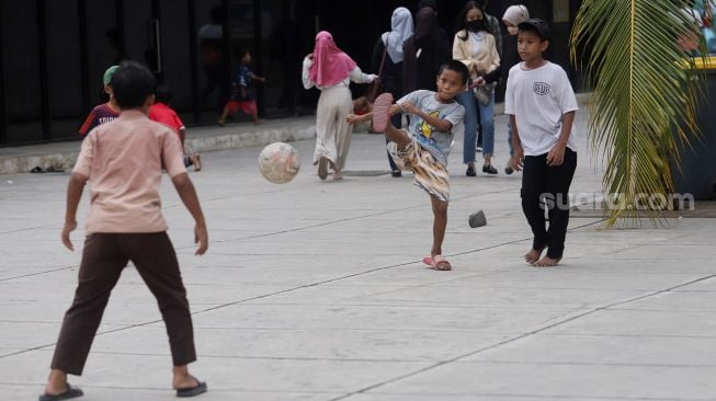 Anak-anak bermain bola di Trotoar Taman Ismail Marzuki, Kamis, Jakarta (14/7).  [Suara.com/Oke Atmaja]
