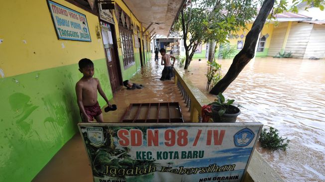 Sejumlah anak bermain air saat banjir menggenangi SDN 98 Kota Jambi di Kota Baru, Jambi, Jumat (15/7/2022).  ANTARA FOTO/Wahdi Septiawan
