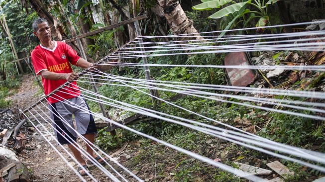 Pekerja melakukan proses pemintalan benang di Kawasan Kebayoran, Jakarta Selatan, Jumat (15/7/2022). [Suara.com/Alfian Winanto]