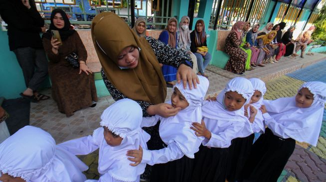 Orang tua siswa memperbaiki jilbab anaknya saat berlangsung perkenalan lingkungan bagi siswa baru pada hari pertama masuk sekolah di SDN-1 Lhokseumawe, Aceh, Jumat (15/7/2022). ANTARA FOTO/Rahmad