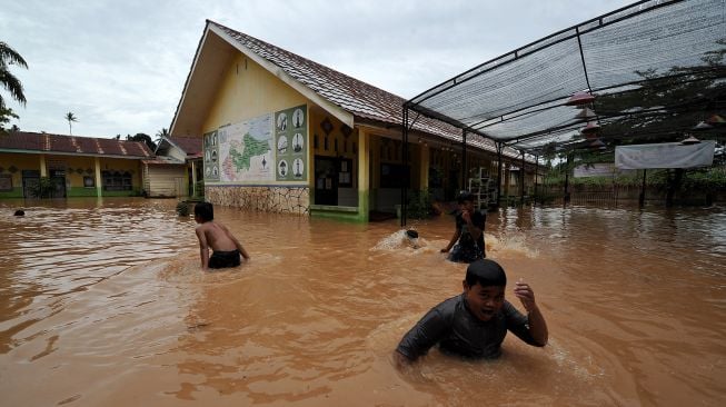 Sejumlah anak bermain air saat banjir menggenangi SDN 98 Kota Jambi di Kota Baru, Jambi, Jumat (15/7/2022).  ANTARA FOTO/Wahdi Septiawan
