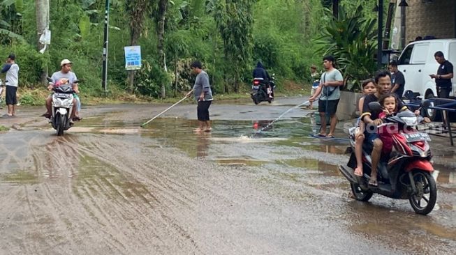 Warga mulai membersihkan lumpur pasca banjir yang meredam di Villa Pamulang, Tangerang Selatan, Sabtu (16/7/2022) (Suara.com/Wivy Hikmatullah)