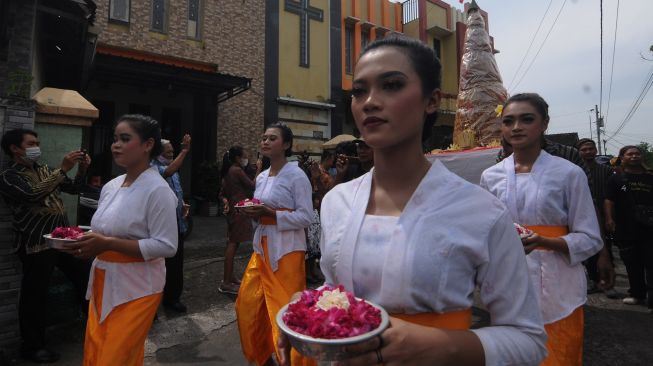 Warga berjalan di depan Gereja Kristen saat mengikuti Kirab Cethik Geni di Gatak, Delanggu, Klaten, Jawa Tengah, Minggu (17/7/2022).[ANTARA FOTO/Aloysius Jarot Nugroho/aww]