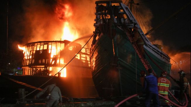 Petugas Dinas Pemadam Kebakaran Kota Surabaya memadamkan kapal kargo yang terbakar di Pelabuhan Kalimas Surabaya, Jawa Timur, Minggu (17/7/2022). [ANTARA FOTO/Didik Suhartono/aww]