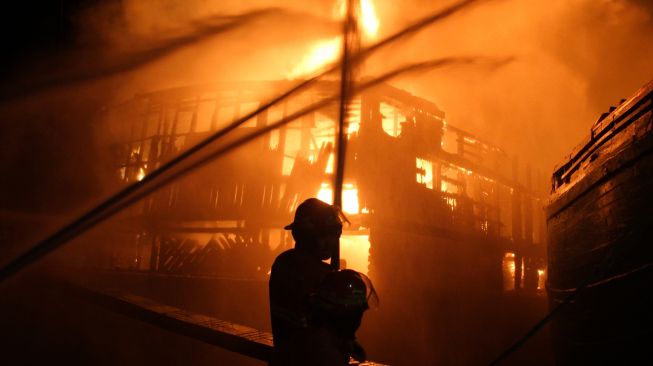 Petugas Dinas Pemadam Kebakaran Kota Surabaya memadamkan kapal kargo yang terbakar di Pelabuhan Kalimas Surabaya, Jawa Timur, Minggu (17/7/2022). [ANTARA FOTO/Didik Suhartono/aww]