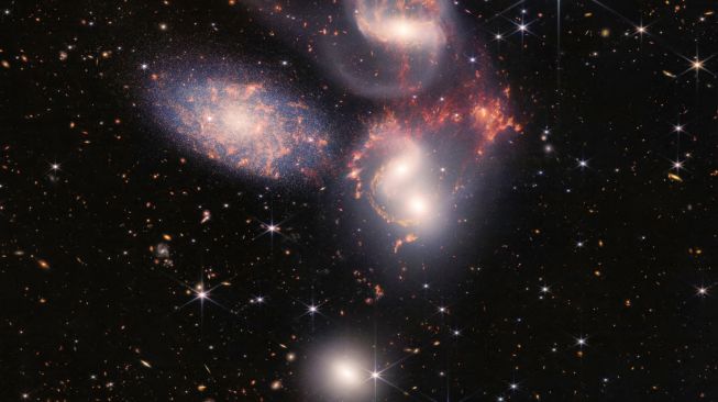 Gambar hasil jepretan Teleskop Luar Angkasa James Webb (JWST) menunjukkan Kuintet Stephan yang terdiri dari lima galaksi yang saling terikat dalam pergerakan hingga menimbulkan tarian kosmik. Kelima galaksi dari Stephan's Quintet ini juga dikenal sebagai Hickson Compact Group 92 (HCG 92), dirilis NASA pada Selasa (12/7/2022). [NASA / ESA / Webb / AFP] 