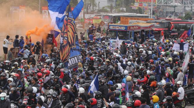 Suporter kesebelasan Arema FC (Aremania) melakukan konvoi di pintu keluar jalan tol Malang-Pandaan di Karanglo, Malang, Jawa Timur, Senin (18/7/2022). [ANTARA FOTO/Ari Bowo Sucipto/hp]