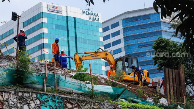 Pekerja beraktivitas di TKP kebocoran gas di proyek revitalisasi Halte Transjakarta Cawang, Jakarta Timur, Rabu (20/7/2022). [Suara.com/Alfian Winanto]