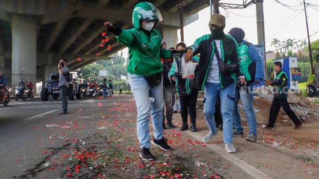 Warga sekitar saat menggelar aksi tabur bunga di Jalan Transyogi Cibubur, Bekasi, Jawa Barat, Rabu (20/7/2022). [Suara.com/Alfian Winanto]