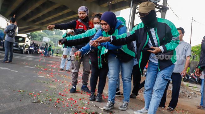 Warga sekitar saat menggelar aksi tabur bunga di Jalan Transyogi Cibubur, Bekasi, Jawa Barat, Rabu (20/7/2022). [Suara.com/Alfian Winanto]