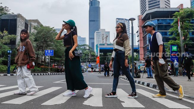 Sejumlah remaja berpose saat difoto di Kawasan Dukuh Atas, Jakarta Pusat, Rabu (6/7/2022). [Suara.com/Alfian Winanto]