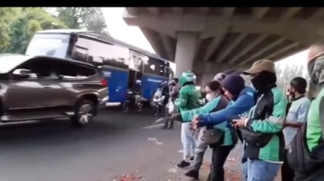 Sejumlah ojol melakukan aksi tabur bunga di lokasi jalan Alternatif Cibubur yang tewaskan 10 orang (Instagram/ @fakta.jakarta).