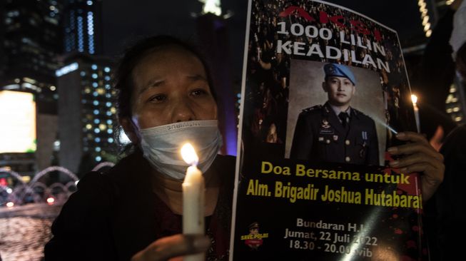 Peserta aksi dari Tim Advokat Penegakan Hukum dan Keadilan (TAMPAK) memegang poster saat aksi seribu lilin dan doa bersama untuk Alm Brigadir Yosua Hutabarat di Bundaran HI, Jakarta, Jumat (22/7/2022).  ANTARA FOTO/Muhammad Adimaja