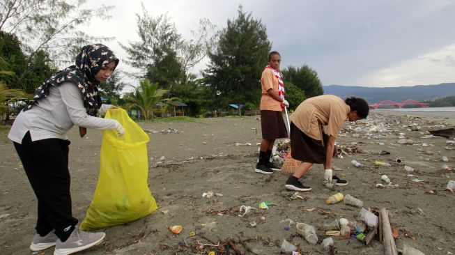 Seorang guru bersama siswinya membersihkan sampah-sampah plastik di pesisir Teluk Youtefa, Jayapura, Papua, Sabtu (23/7/2022). ANTARA FOTO/Gusti Tanati
