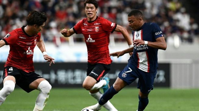 Penyerang Paris Saint-Germain, Kylian Mbappe (kanan) berlari dengan bola melewati bek Urawa Red Diamonds Takuya Iwanami (kiri) selama laga persahabatan Urawa Red Diamonds vs PSG di Stadion Saitama di Saitama pada 23 Juli 2022.Toshifumi KITAMURA / AFP.